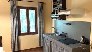 A compact kitchen with a built-in stove, a sink, and a window with curtains.