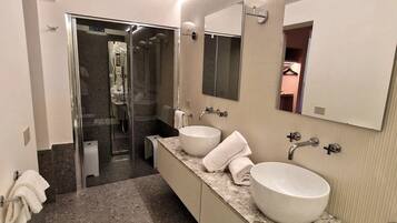 Ein modernes Badezimmer mit einer großen Badewanne, zwei Waschbecken und einer begehbaren Dusche.