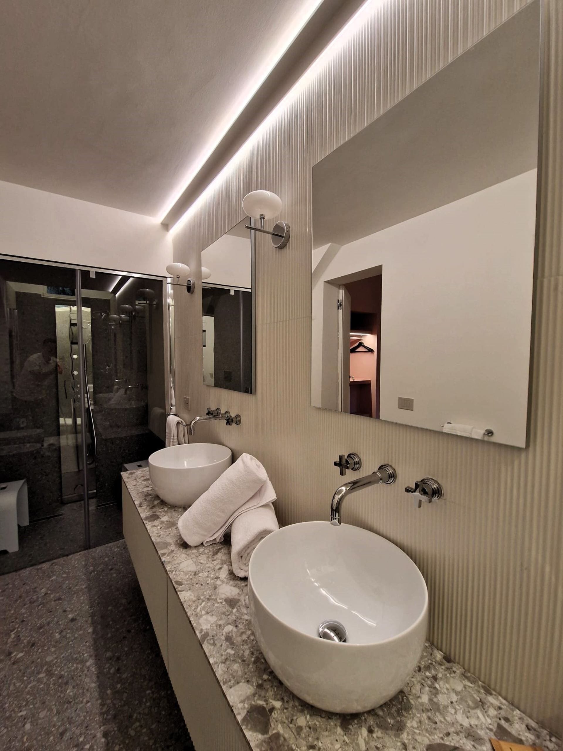 Un bagno moderno con due ampi lavabi, una doccia a filo pavimento e un grande specchio.