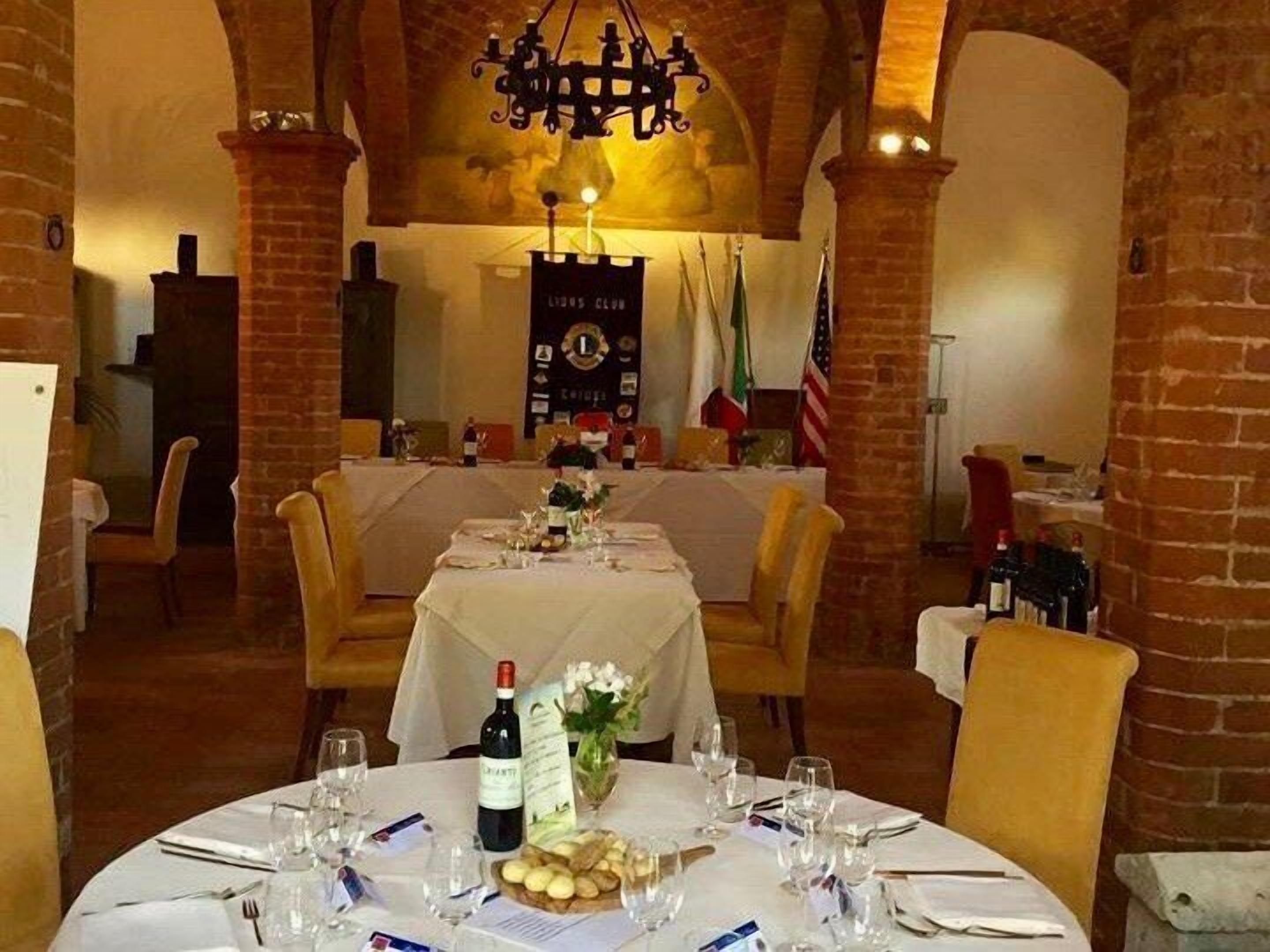 A dining area with a brick wall, a chandelier, and a table set for a meal.