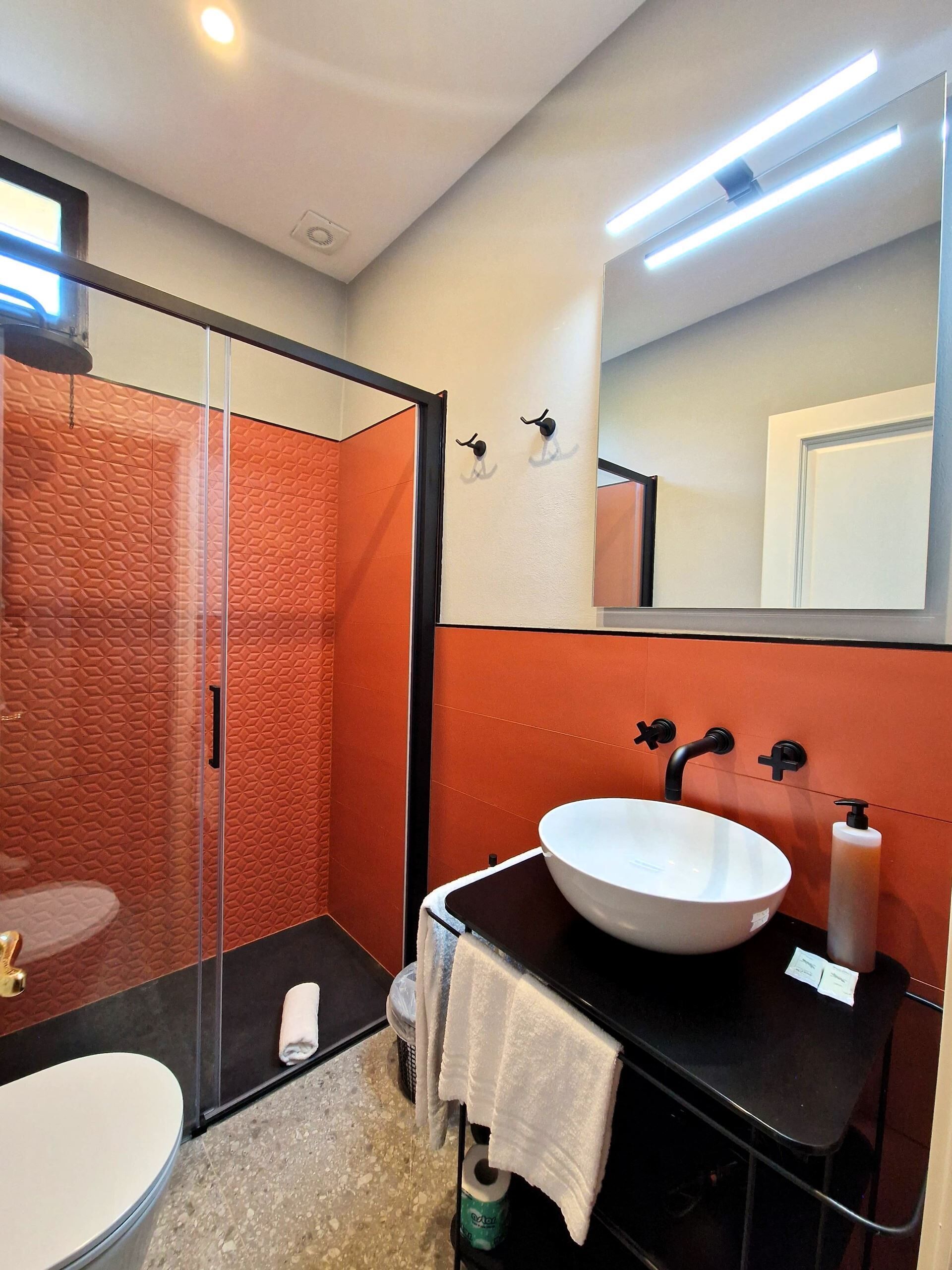 A modern bathroom with a glass shower enclosure, a white sink with a black faucet, and a mirror above the sink.