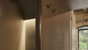 A modern bathroom with a minimalist design, featuring a shower area, a towel rack, and a visible outdoor view through a glass door. - Borgo Dolciano (Chiusi)