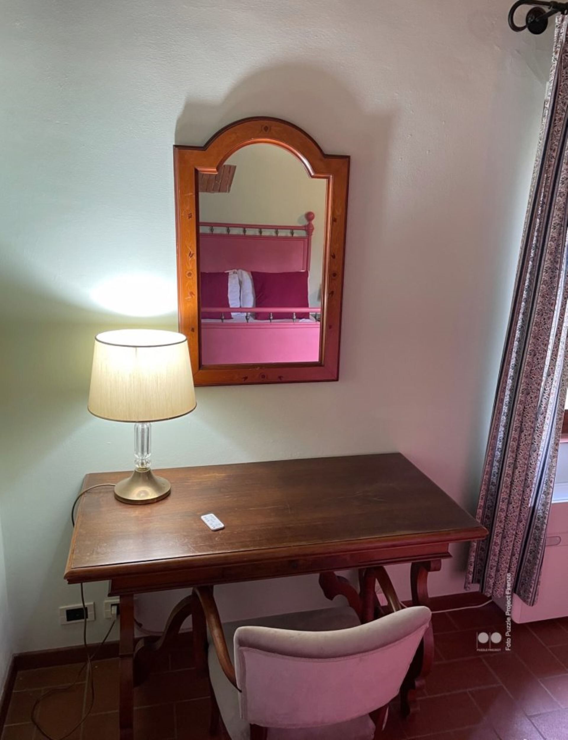 Una scrivania in legno con una lampada, una sedia e uno specchio appeso al muro.