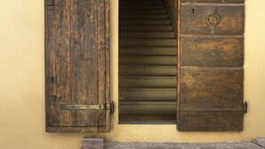A building entrance with a wooden door and a lantern on the wall. - Borgo Dolciano (Chiusi)