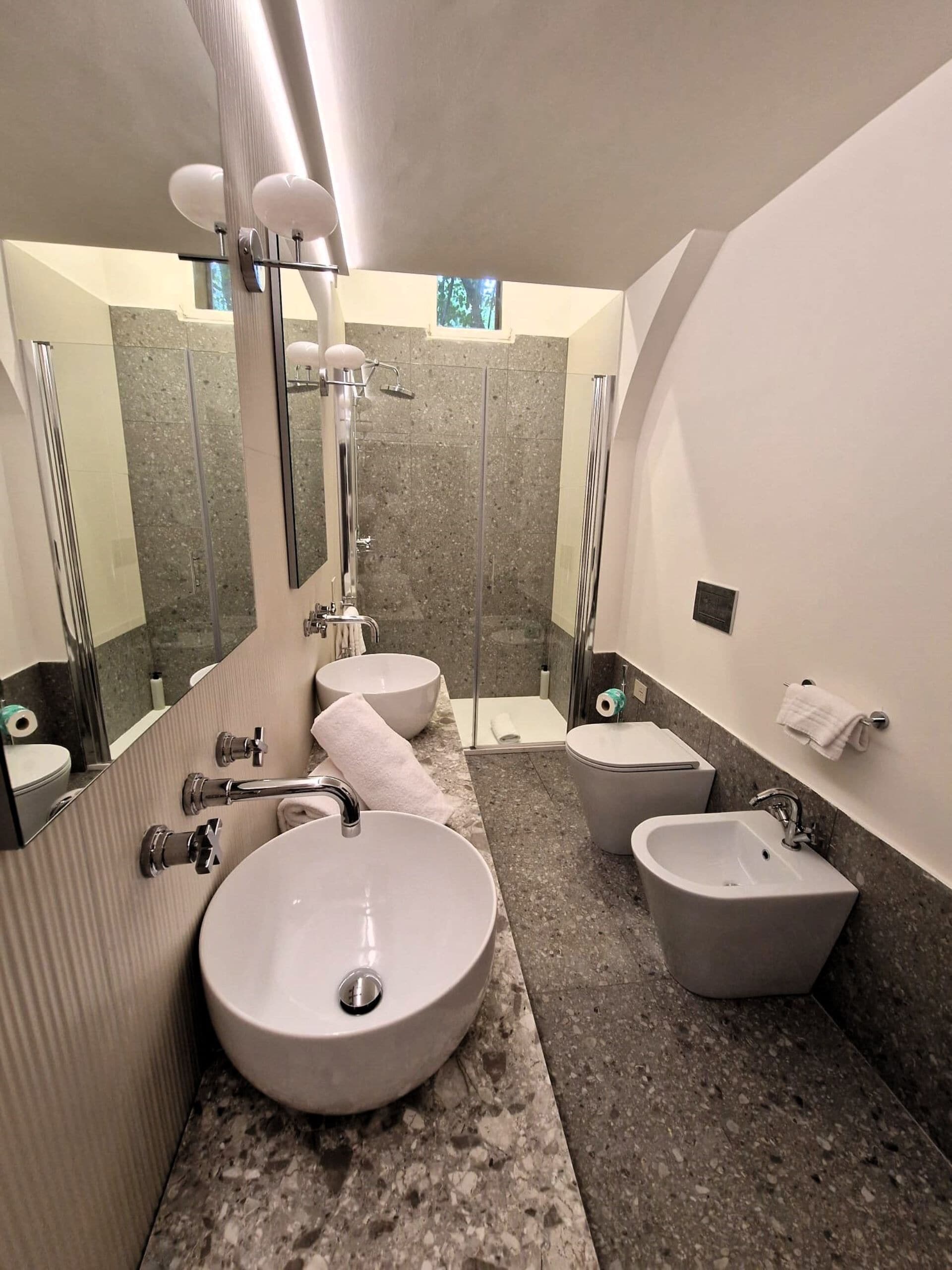 A modern bathroom with two sinks, a shower, and a toilet.