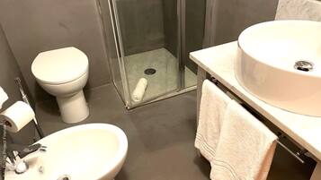 A bathroom with a toilet, bidet, and sink.