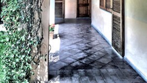 Un couloir étroit avec un plafond en bois et un sol carrelé, qui mène à une porte au fond.