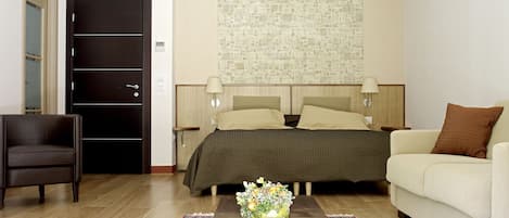 A hotel room with a bed, a sofa, a chair, a coffee table, and a decorative wall.