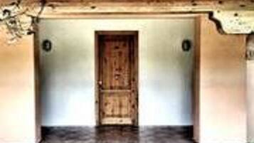 Ingresso di un edificio con porta in legno, pavimento piastrellato e piccolo giardino.