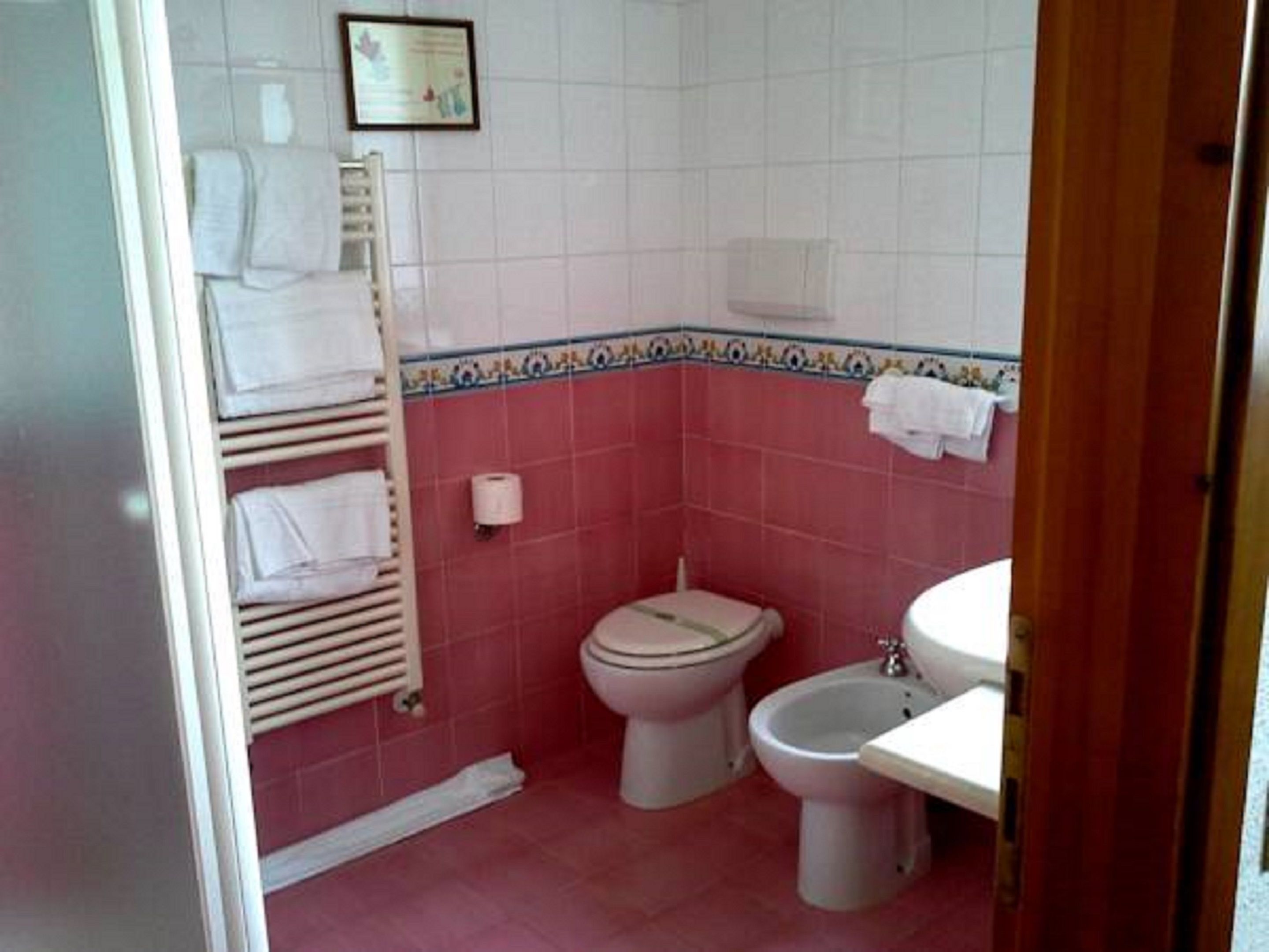 A bathroom with a toilet, bidet, and a towel rack with towels.