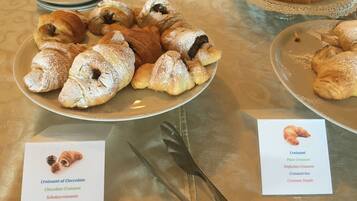 Ein Tisch mit Tellern voller Croissants und einer Speisekarte, die verschiedene Croissant-Sorten auflistet.