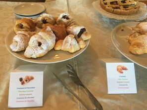 A table with plates of croissants and a menu listing different types of croissants. - Hotel Pulicinu (Arzachena)