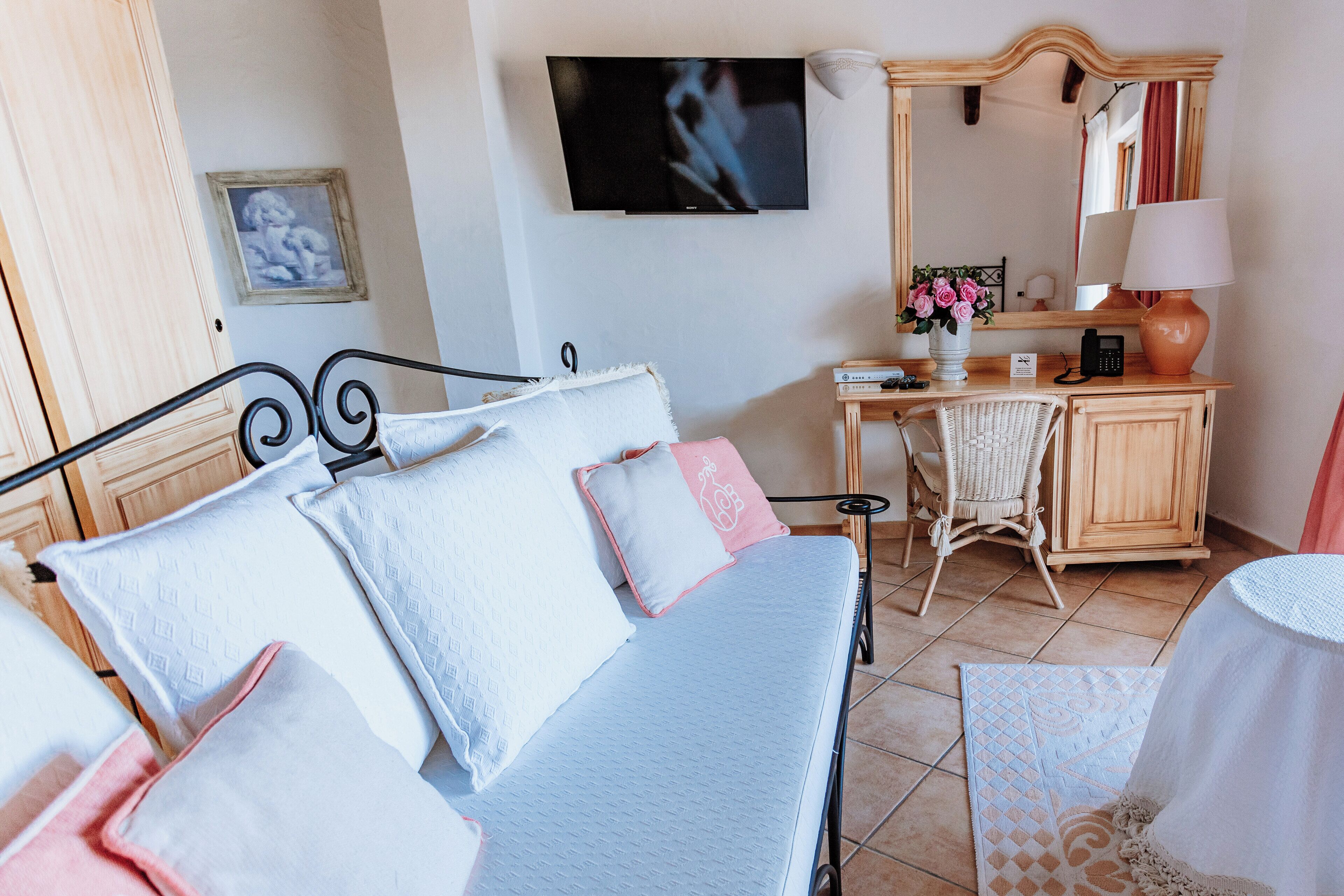 Un dormitorio con cama, escritorio, silla, televisor y espejo.