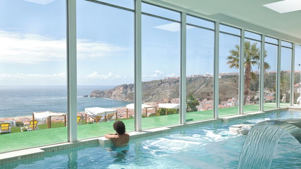 Piscina com vista para o mar e uma cascata.