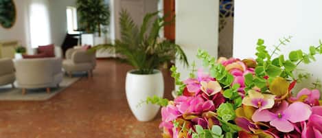 A hotel lobby with a large potted plant, a seating area with sofas, and a decorative wall.