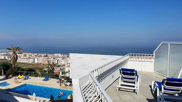A rooftop pool with clear views of the ocean and cityscape.