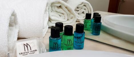 A bathroom with a white sink, a mirror, and toiletries including shampoo and body wash bottles.