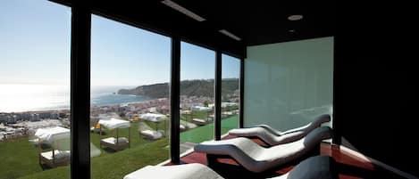 A modern room with large windows overlooking a coastal cityscape.