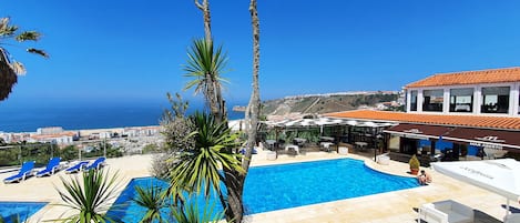 Una piscina al aire libre, sombrillas, tumbonas