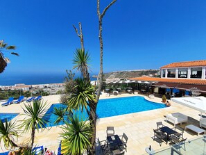 A pool area with lounge chairs, a restaurant, and a view of the sea. - Miramar Hotel & Spa (Nazaré)