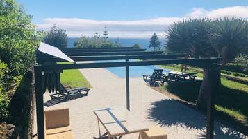 A patio area with a pool, lounge chairs, and a view of the ocean.