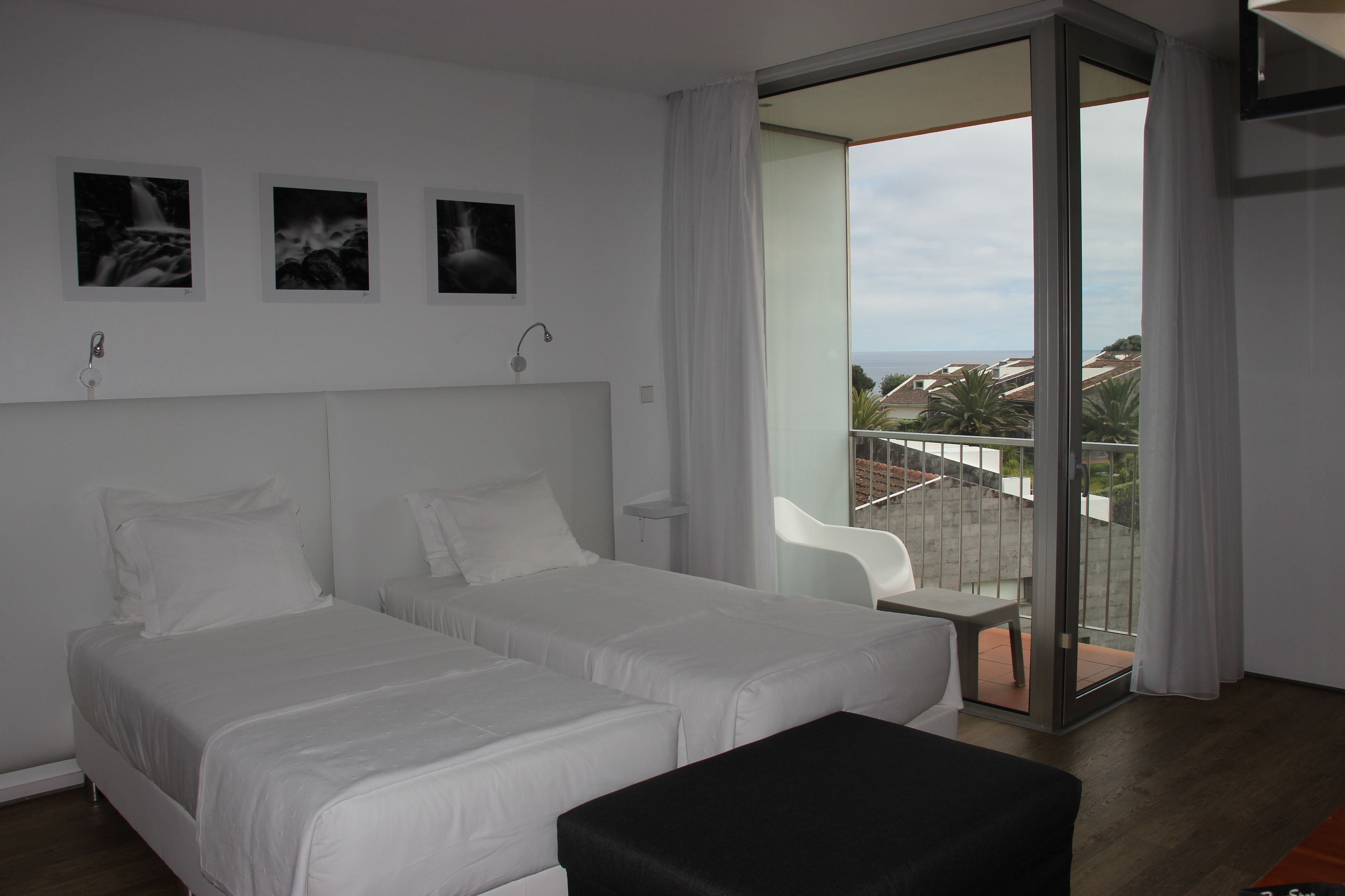 Una habitación de hotel moderna con dos camas, un balcón con vistas y un ventanal corredizo.