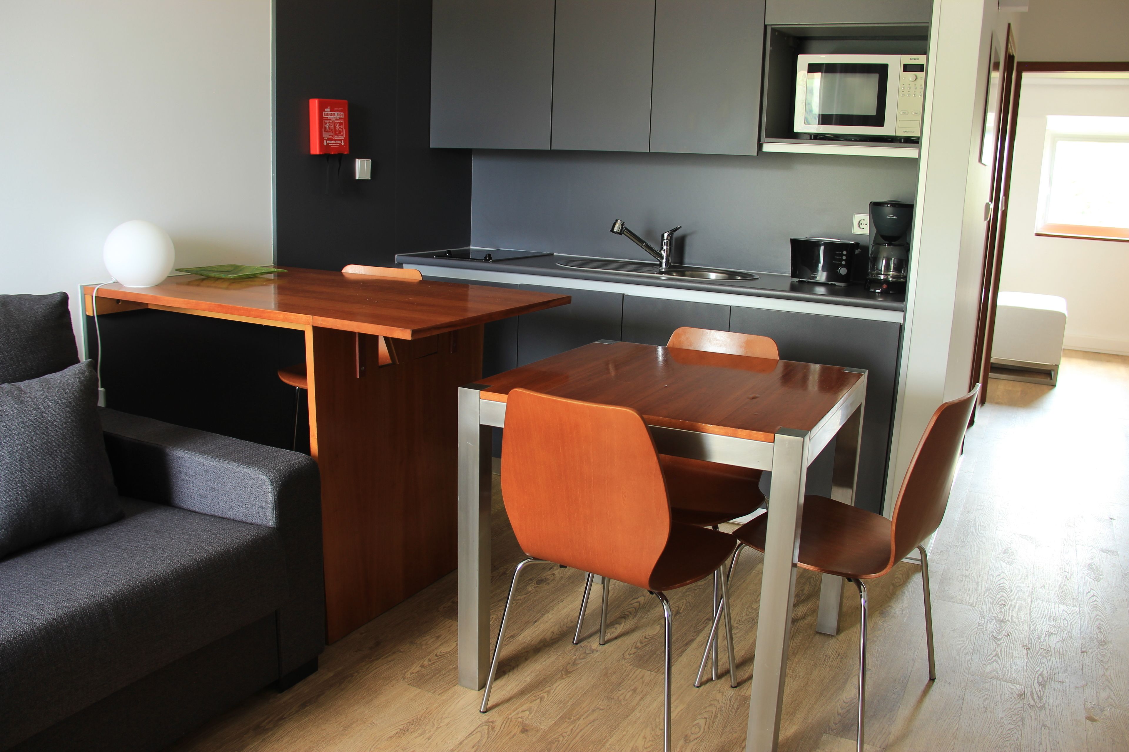 Una cucina moderna con zona pranzo, che include un tavolo e sedie di legno, un divano e un forno a microonde.