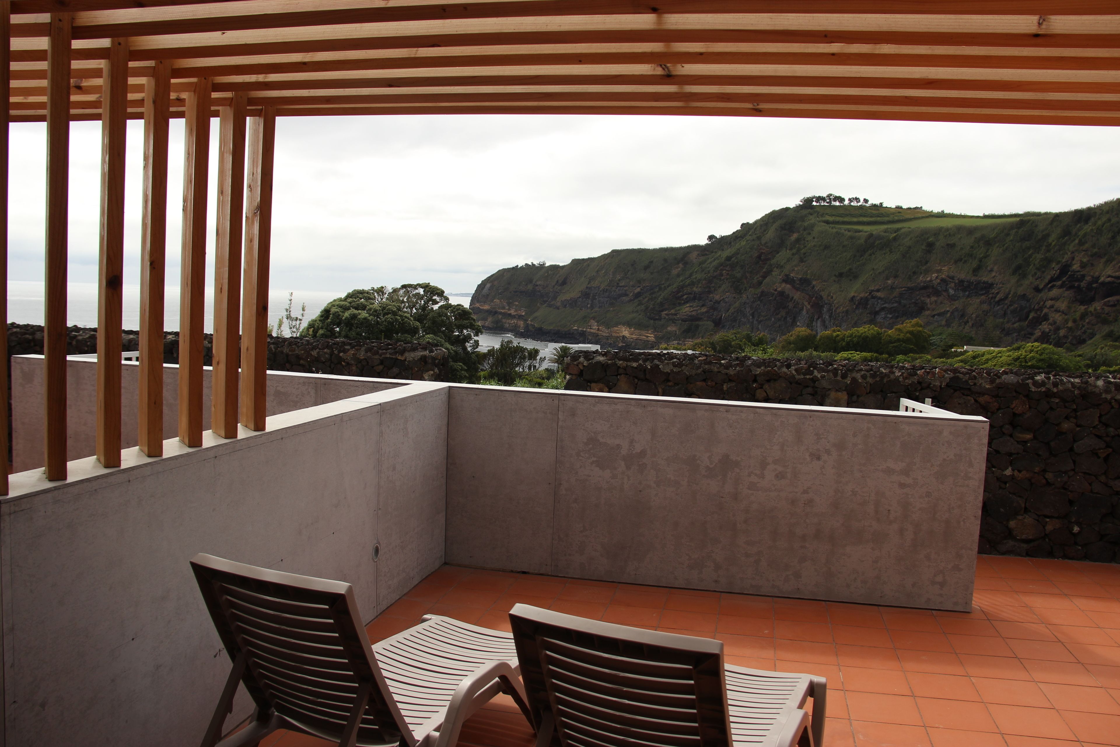 A balcony with two chairs and a view of a coastal landscape.