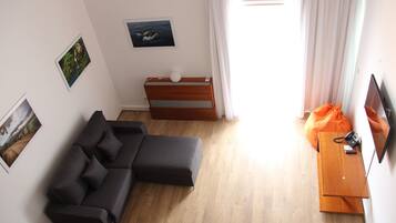 Una sala de estar moderna con un sofá modular, una mesita de madera y un televisor de pantalla plana.