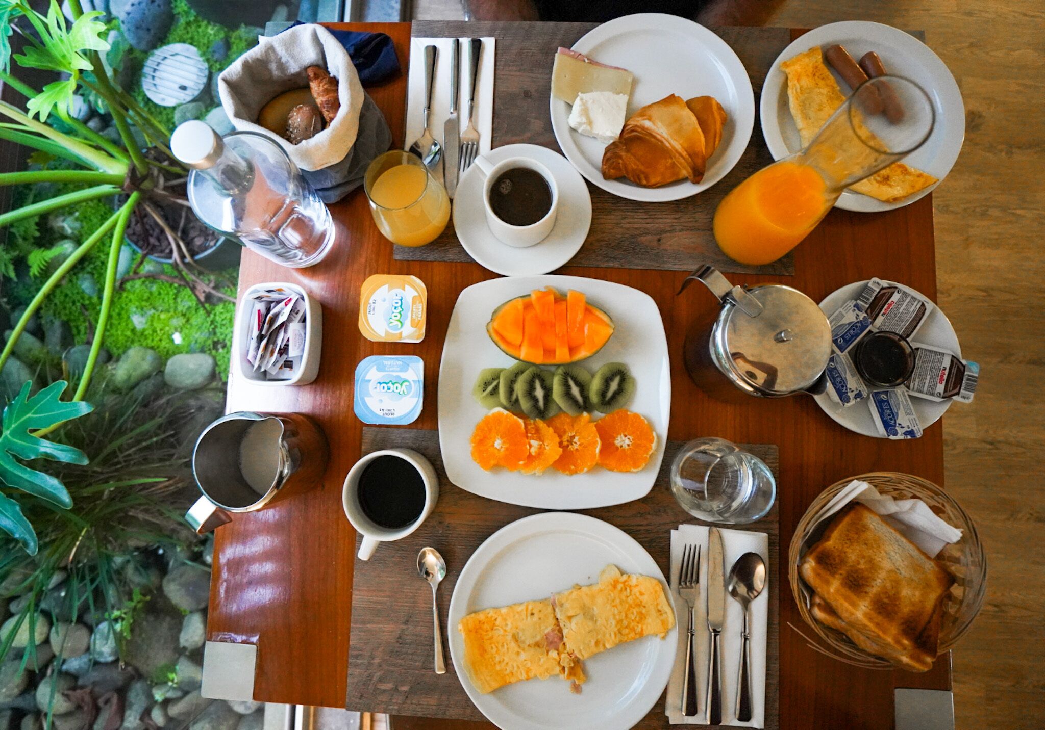 Een ontbijttafel met diverse soorten eten, zoals fruit, gebak en drankjes.