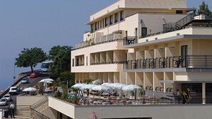 Un hotel de varios pisos con balcones, mobiliario exterior y una vista despejada del entorno.