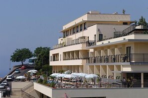 Ein mehrgeschossiges Hotel mit Balkonen, Außenbereich zum Sitzen und freiem Blick auf die Umgebung.