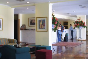 Eine Hotelhalle mit einer Rezeption, einer Couch und einer Kaffeemaschine.