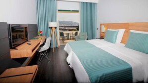 Habitación de hotel con cama, escritorio, silla y vista a la ciudad por la ventana.