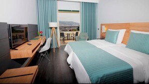 Ein Hotelzimmer mit Bett, Schreibtisch, Stuhl und Blick auf die Stadt durch das Fenster.