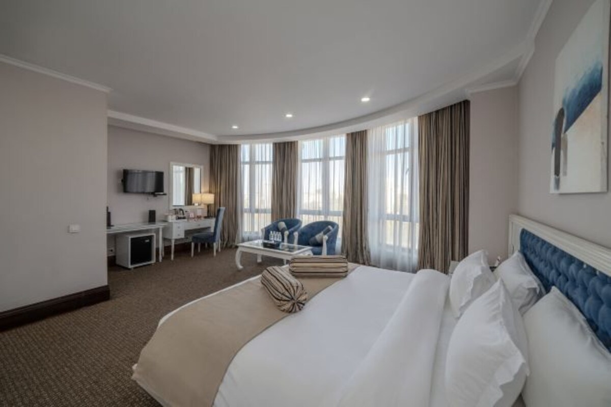 A hotel room with a large bed, a desk, a chair, and a television.