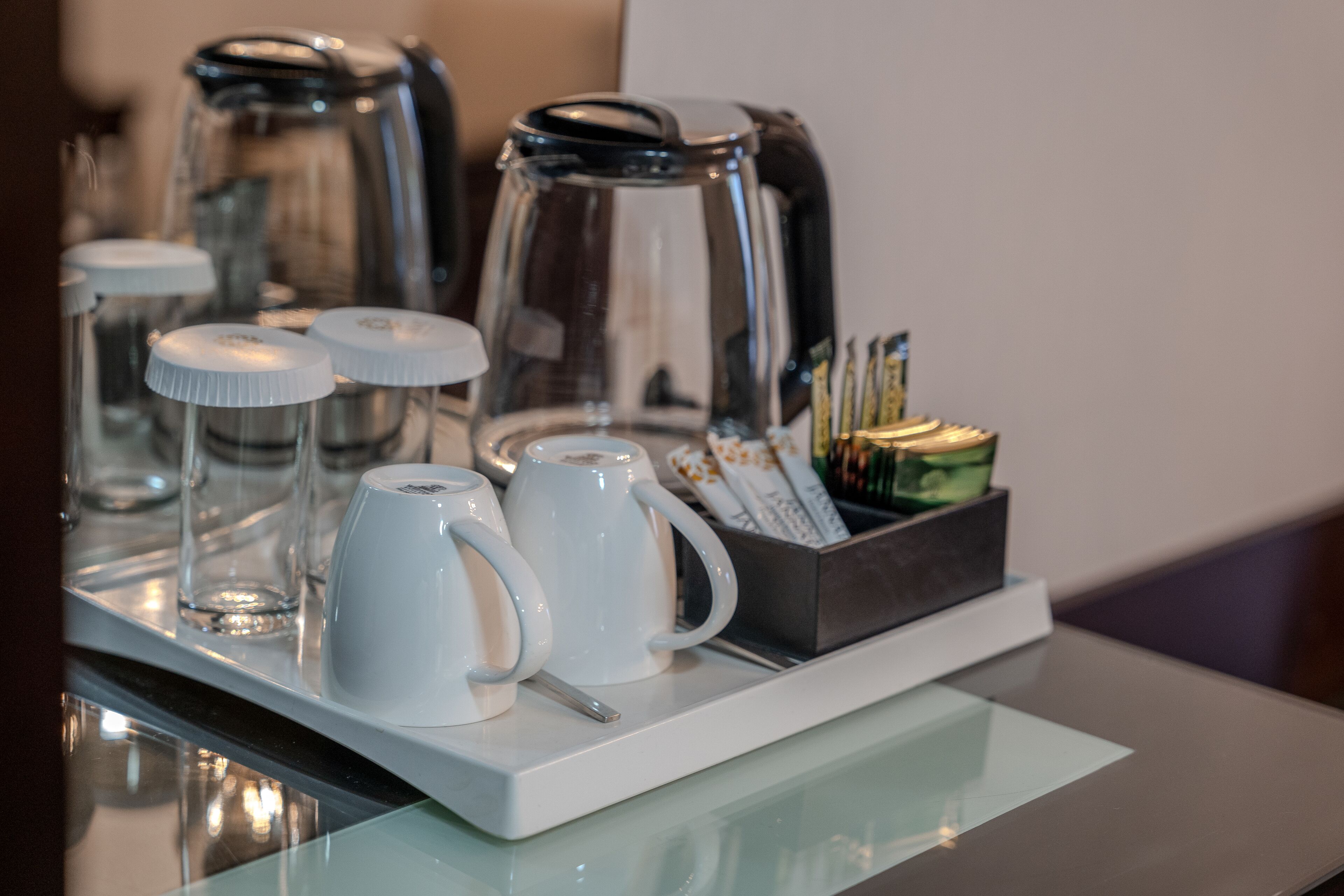 A coffee station with a coffee maker, mugs, and a tray of coffee pods.