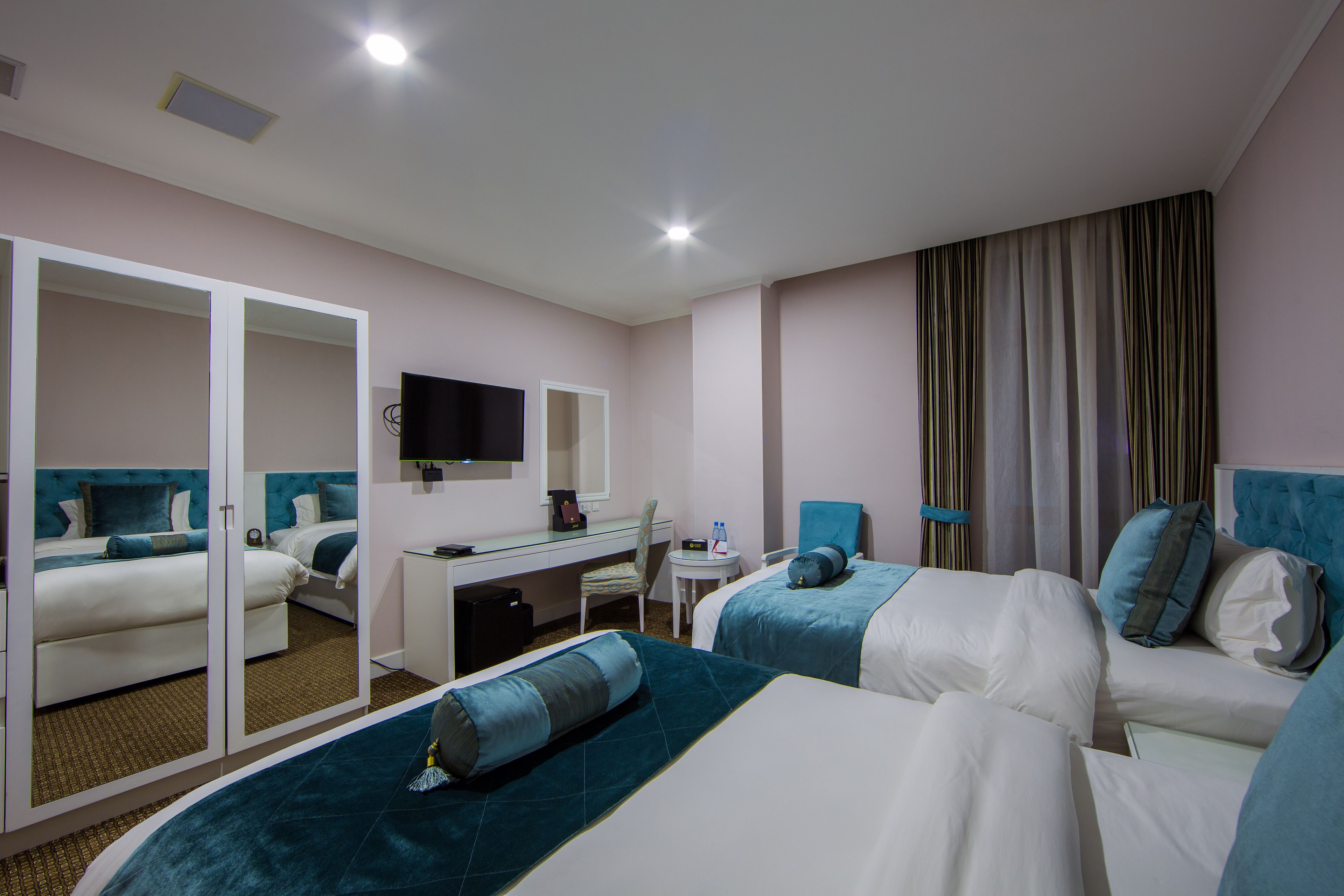 Une chambre d’hôtel avec deux lits, un bureau, une chaise, une télévision et un miroir.