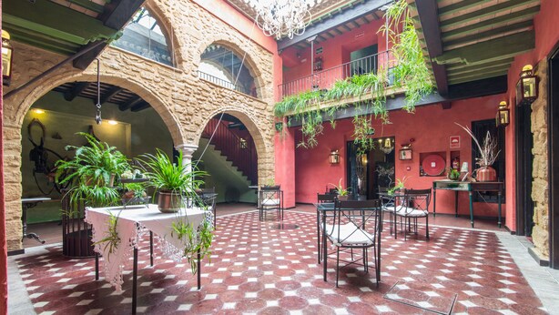 Un patio con piso a cuadros, plantas en macetas y una escalera que sube a un nivel superior.