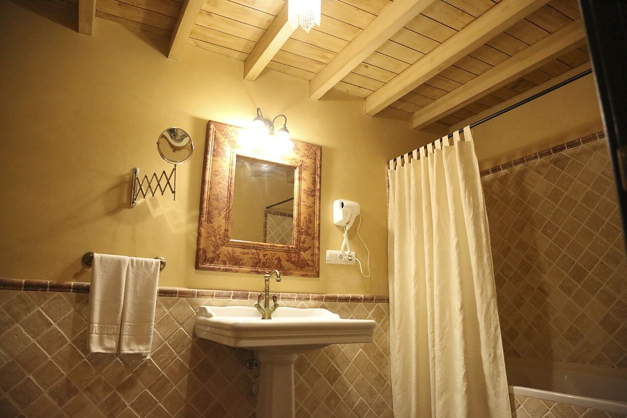 A bathroom with a sink, mirror, towel rack, and shower curtain.