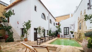 Un patio con piscina, mobiliario exterior y plantas en macetas.