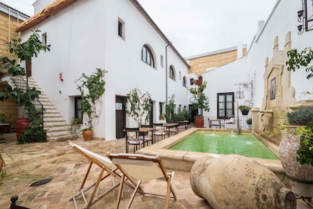 Una piscina al aire libre, sillones reclinables de piscina