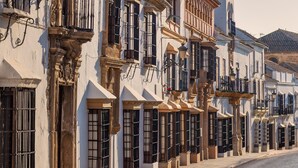 Filas de edificios blancos con balcones y ventanas amplias a lo largo de una calle adoquinada.