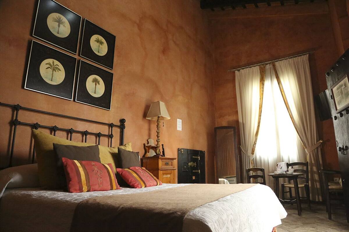 Un dormitorio con cama, mesita de noche, lámpara, silla y mesa.