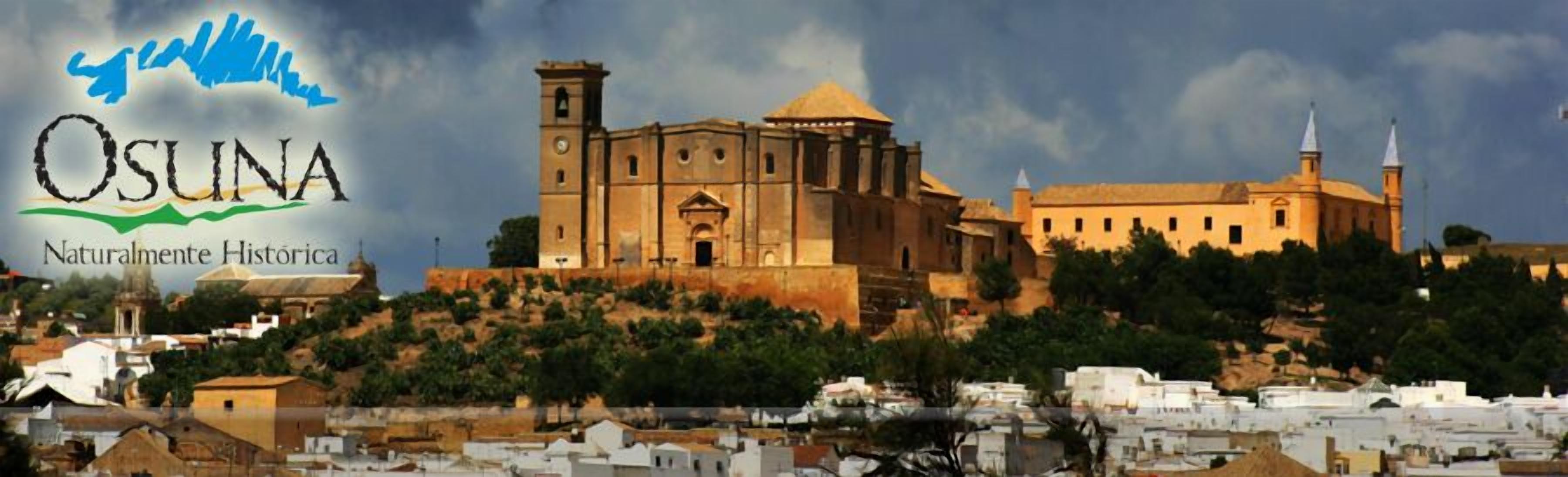 Un edificio histórico con una imponente torre de campanas y una cúpula, rodeado de un paisaje montañoso con abundante vegetación.