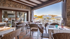 Un espace extérieur aménagé pour les repas, avec des murs en pierre, des meubles en osier et des parasols.