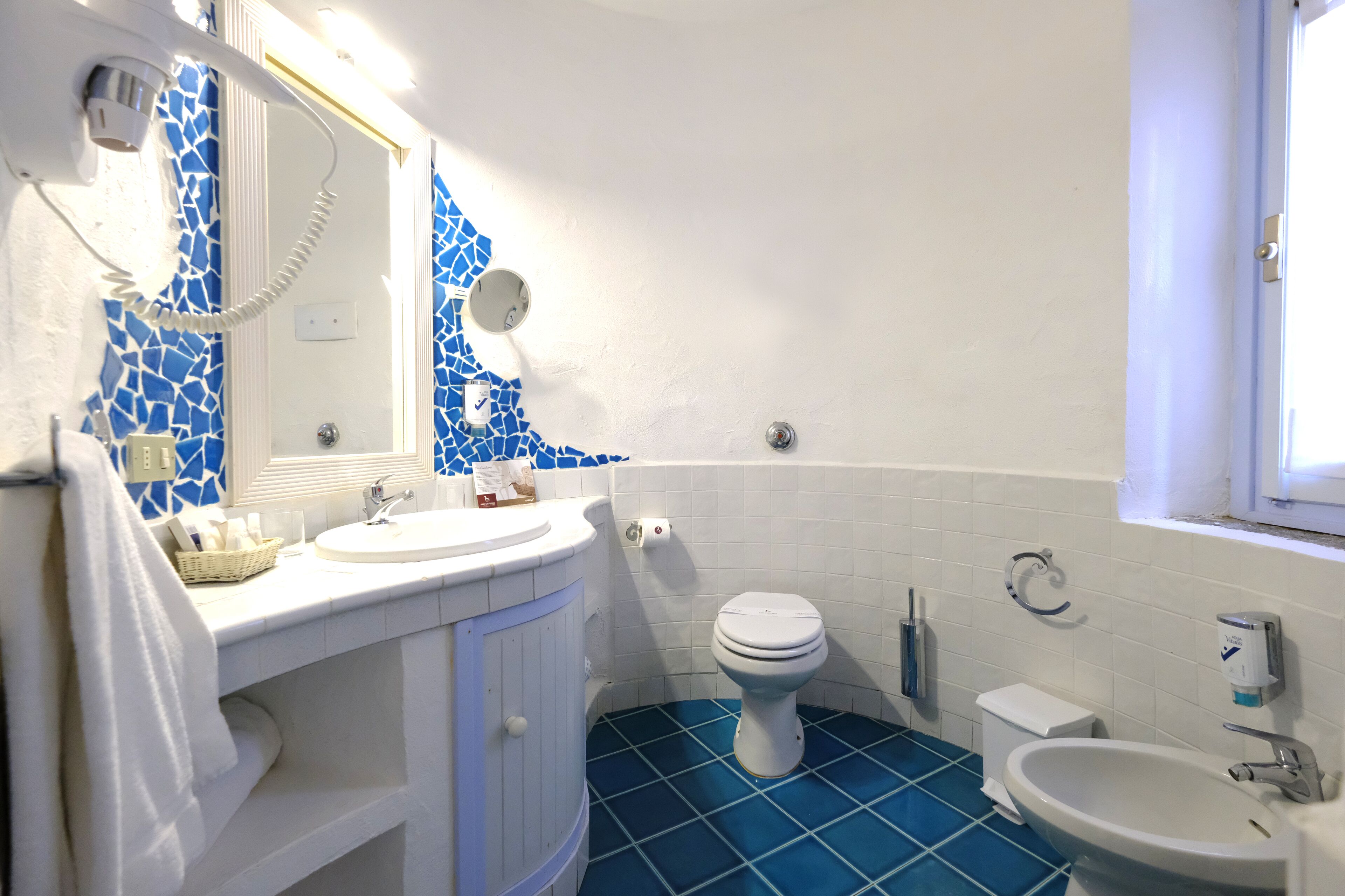 Une salle de bain avec un lavabo blanc, des toilettes et un bidet.