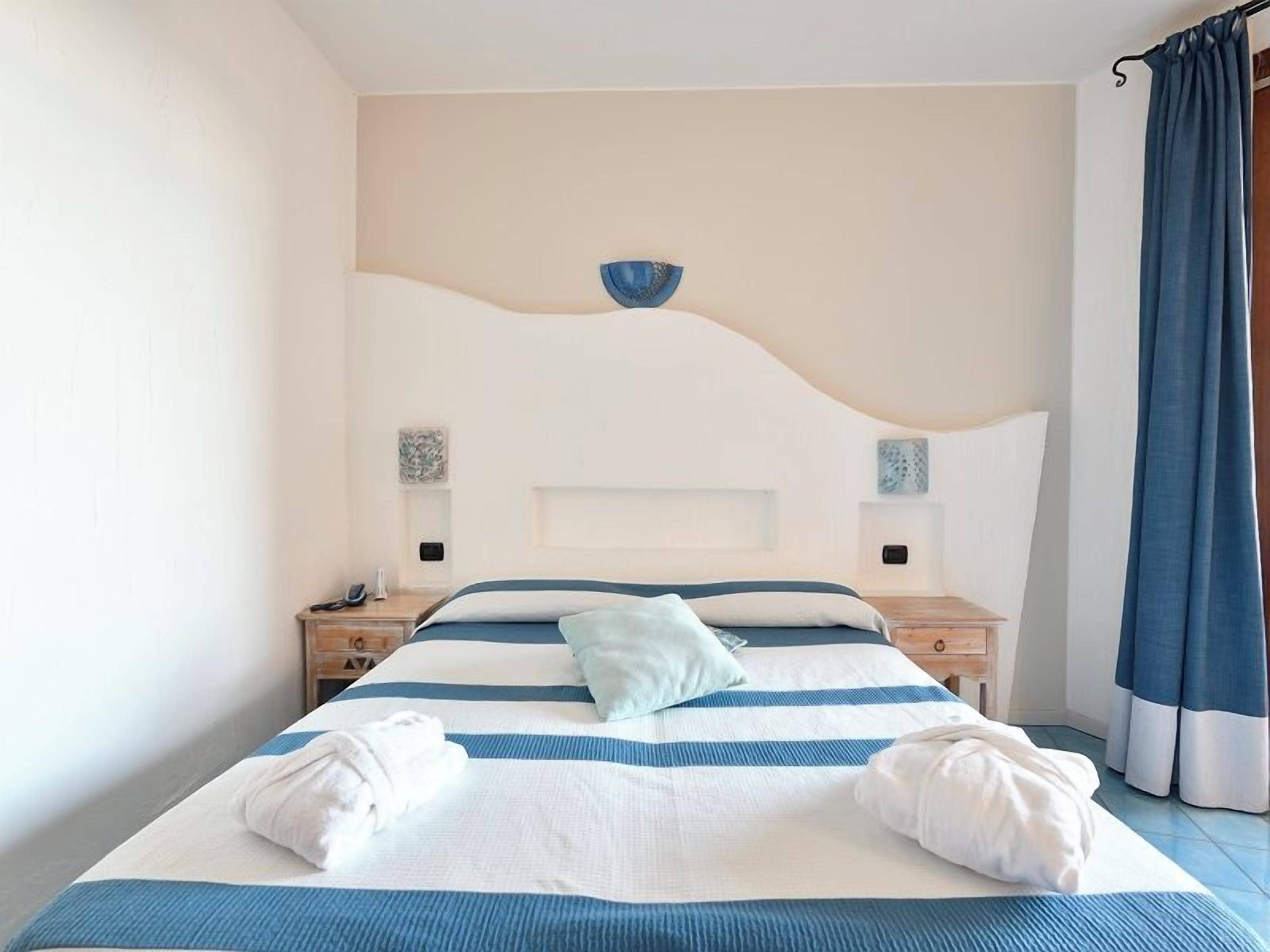 Ein Hotelzimmer mit einem Bett, zwei Nachttischen, einer Stehlampe und einer Wandleuchte.