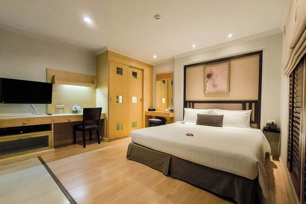 A hotel room with a bed, a desk, a chair, a TV, and a wardrobe.