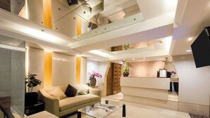 Eine moderne Hotellobby mit einer Rezeption, einer Sitzecke und einer Treppe.